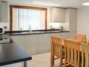 a kitchen with white cabinets and a table and chairs at Christine Cottage in Flamborough