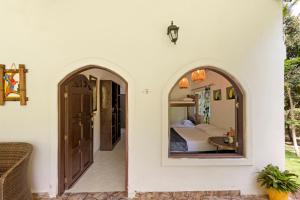 a room with a bed and a bedroom with a mirror at Hostal Casa del Rio in Guachaca