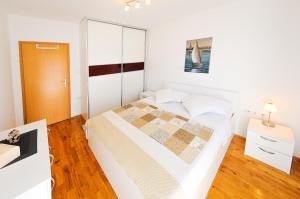 a small bedroom with a bed and a wooden floor at Apartments Rajic in Split