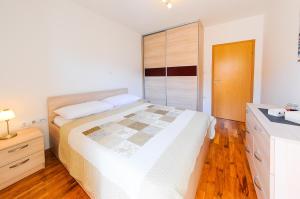 a white bedroom with a bed and a wooden floor at Apartments Rajic in Split