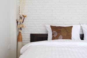 a bedroom with a bed with white sheets and pillows at Kittawan Home&Gallery in Chiang Mai