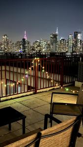 a bench on a balcony with a city skyline at night at 5 mins to Midtown Central New Luxury Corner 2b2b Apt with Amazing City View in Long Island City