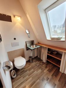 a bathroom with a toilet and a window at Ferienhaus ROSA mit Sauna in Dorum-Neufeld