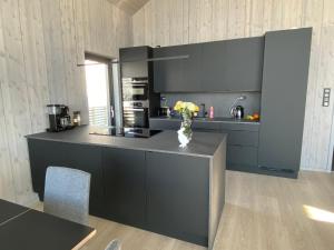 una cucina nera con un vaso di fiori su un bancone di The Panoramic Chalet a Stranda