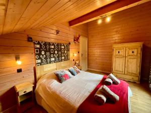 ein Schlafzimmer mit einem Bett in einer Blockhütte in der Unterkunft Le Murmure du Ruisseau, 4 étoiles avec sauna et terrasse in La Bresse