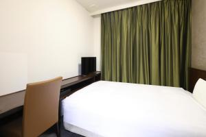 a hotel room with a bed and a green curtain at Dormy Inn Matsumoto in Matsumoto +118 photos
