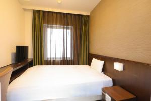 a hotel room with a bed and a window at Dormy Inn Matsumoto in Matsumoto