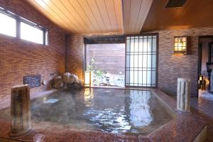 a large pool of water in a room with a brick wall at Dormy Inn Matsumoto in Matsumoto