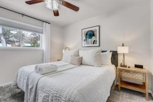 a bedroom with a white bed with a ceiling fan at Cheerful Chalet Centrally Located w BBQ Pit in Colorado Springs