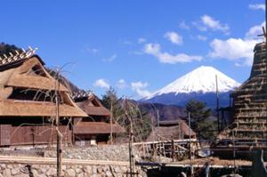 a snow capped mountain in the background of a village with buildings at Guesthouse Sakuya in Fujikawaguchiko