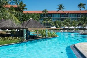 a pool at a resort with palm trees and umbrellas at Flat no Marulhos Suites Resort - unidade C104 Térreo in Porto De Galinhas