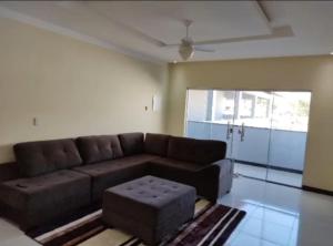 sala de estar con sofá marrón y taburete en Hostel Tia Ró Quartos Feminino e Masculino Lugar de paz, en Governador Valadares