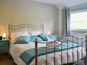 a bedroom with a bed with blue pillows and a window at Briar Rigg in Keswick