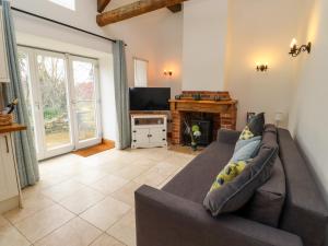 a living room with a couch and a television at Christon Well Cottage in Alnwick
