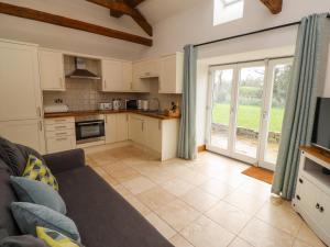 a living room with a couch and a kitchen at Christon Well Cottage in Alnwick