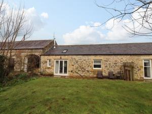 an old stone cottage with a lawn in front of it at Christon Well Cottage in Alnwick