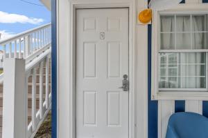 une porte blanche avec une fenêtre à côté d'une chaise bleue dans l'établissement Cabana Beach #5 Condo Steps from the Beach, à Myrtle Beach 28 autres photos