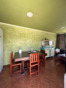 Un comedor con mesa y sillas y una cocina. en El quincho, en San Pedro