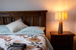 ein Schlafzimmer mit einem Bett mit einer Lampe auf einem Nachttisch in der Unterkunft Brand New 2BR Home in City in Christchurch