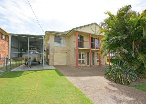 a house with a boat in a garage at Burrumundi - 100M To Beach - Great Water Views - Deck - Air Con - WiFi - Pool Table in Burrum Heads