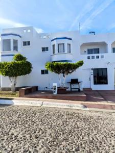 une maison blanche avec des arbres devant dans l'établissement Condominio 231 Loma Bonita, enfrente de la alberca!, à San Carlos