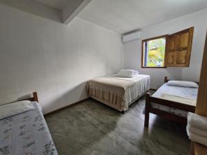 a bedroom with two beds and a window at Pousada Mar de Mamoã in Ilhéus