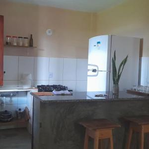 a kitchen with a counter with a refrigerator and stools at Pousada Mar de Mamoã in Ilhéus +66 photos