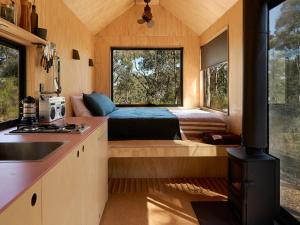 a tiny house with a kitchen and a stove at Secluded off-Grid cabin with water views - Marcel in Chewton