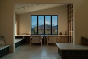 a room with a table and chairs and a large window at 富士山望むプライベートヴィラ 900平方メートルの敷地を貸切利用 憩 ikoi Fuji サウナ 4Kシアター in Fujikawaguchiko