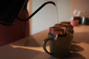 a coffee being poured into a coffee cup on a table at 富士山望むプライベートヴィラ 900平方メートルの敷地を貸切利用 憩 ikoi Fuji サウナ 4Kシアター in Fujikawaguchiko
