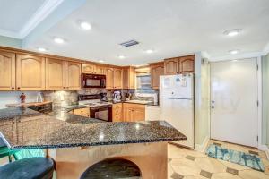 a kitchen with wooden cabinets and a marble counter top at Amelia South - B7 in Fernandina Beach