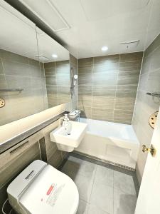 a bathroom with a toilet and a sink and a tub at 동탄호수뷰하버 룸3 in Hwaseong