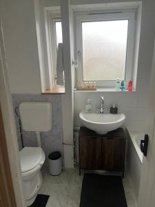 a bathroom with a toilet and a sink and a window at Comfy one bedroom apartment in Barking