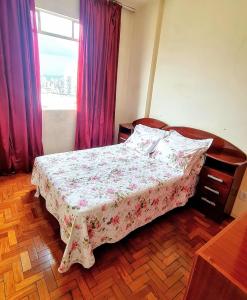 a bedroom with a bed with a floral bedspread and a window at Por do Sol nas alturas! Sua solução no centro de BH in Belo Horizonte +24 photos