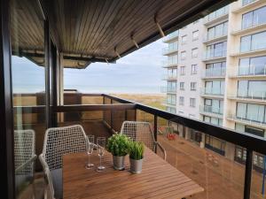 a balcony with a table with wine glasses and plants at Studio by the Beach with Sea View in Oostduinkerke