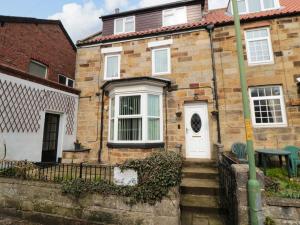 ein Backsteinhaus mit einer weißen Tür und einer Treppe in der Unterkunft Florence Cottage in Saltburn-by-the-Sea