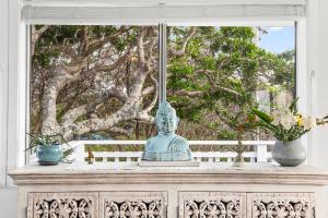 eine Statue, die auf einem Tisch vor einem Fenster sitzt in der Unterkunft Pipe Dream - River Frontage with Amazing Views in Wooli