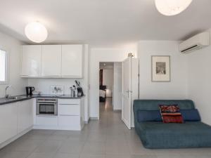 a kitchen and living room with a blue couch in it at Les jardins de Trevi in La Garonnette-Plage