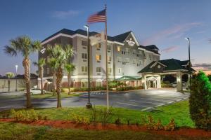 Country Inn & Suites by Radisson, St Petersburg - Clearwater, FL في بينيلاس بارك: فندق مع العلم الامريكي في مواقف السيارات