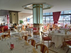 a restaurant with white tables and chairs and windows at Jura Hotel Restaurant Le Panoramic in Saint-Claude