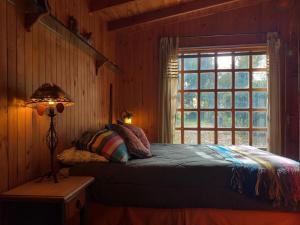 a bedroom with a bed next to a window at Casona Pidenco, 3km de curacautín in Curacautín