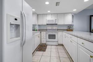 a white kitchen with white appliances and white cabinets at Striking Oceanview Condo in Fernandina Beach