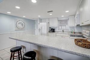 a kitchen with white cabinets and a counter with stools at Striking Oceanview Condo in Fernandina Beach