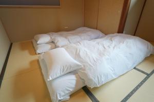una camera con due letti con lenzuola e cuscini bianchi di Rikka Soyuji Hinoki Woodbath 2 bedrooms Kitchen Free parking a Takayama