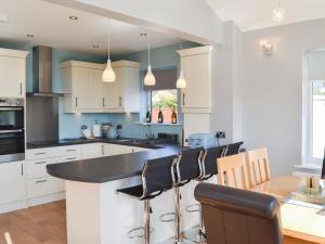 a kitchen with white cabinets and a black counter top at Grays Cottage in Sewerby