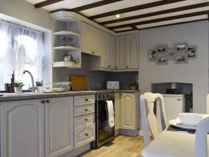 een keuken met witte kasten, een wastafel en een tafel bij Wilma Cottage in Geldeston