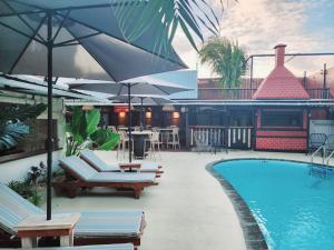 a pool with chairs and umbrellas next to a building at The Rustic Vintage Suite in Grand Baie