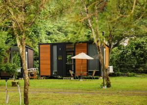 a cabin with a table and an umbrella in the grass at Yiyouguo 2 by Tiny Away in Guoxing