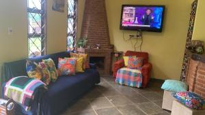 a living room with a couch and a tv at Chácara do Maurão - tranquility and nature in Serra Negra