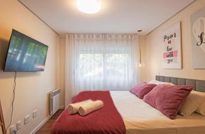 a bedroom with a bed with red pillows and a television at Locar - in Canela Villaggio Caracol Novissimo in Canela
